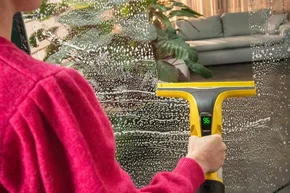 Person reinigt Fenster mit Gerät.